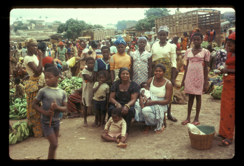 Seated woman surrounded in market by daughters and children